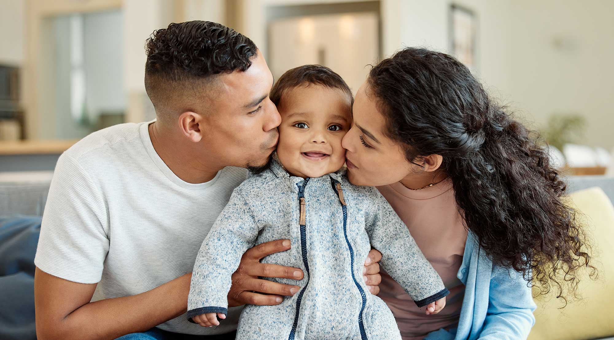 Parents kissing baby